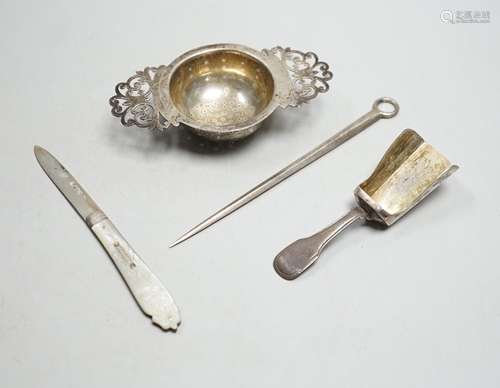 A silver tea strainer, a George III silver shovel caddy spoo...