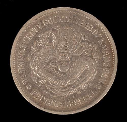 A Chinese silver coin, one side with relief of a dragon, the...