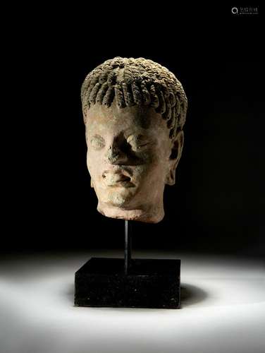 A CARVED STONE BUST OF AN ATTENDANT, GANDHARA CIRCA 5TH CENT...