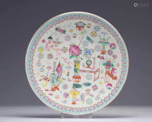 Plat en porcelaine de chine famille rose  à décor de mobilie...