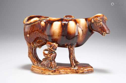 A 19TH CENTURY STAFFORDSHIRE TREACLE-GLAZED POTTERY COW CREA...