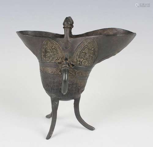 A Chinese bronze jue vessel of typical form with cast mask a...