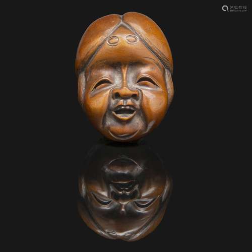 NETSUKE en bois, représentant un masque d'Okame, riant. Sign...