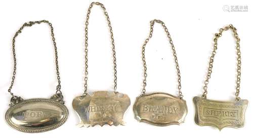 Four decanter labels including two silver examples, comprisi...