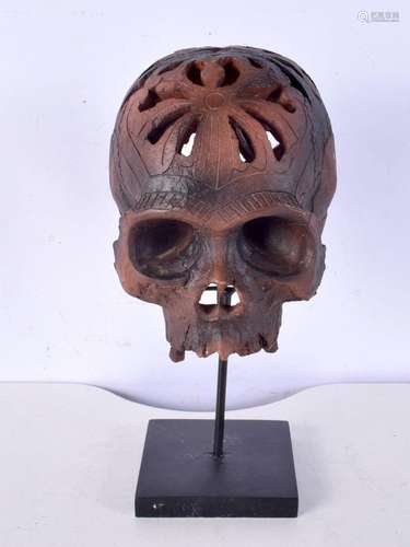 A stylised skull mounted upon a squared form plinth. 30 cm h...