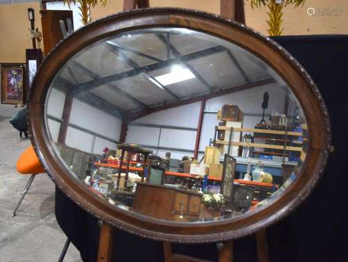 A large oval wooden framed bevelled glass mirror 83 x 116 cm