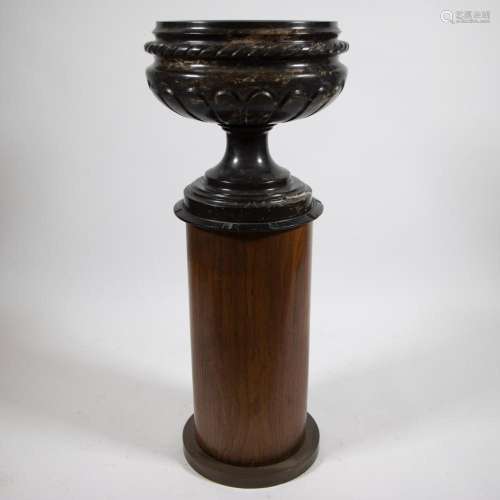 Beautiful lightly veined black marble garden vase on a woode...