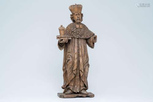 A large wood sculpture of Saint Damian holding a book and an...