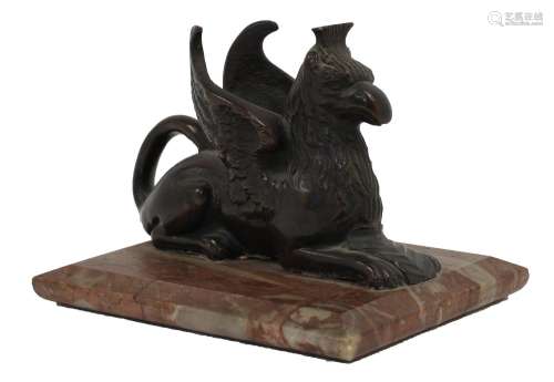 A bronze model of a seated griffin atop a rectangular marble...