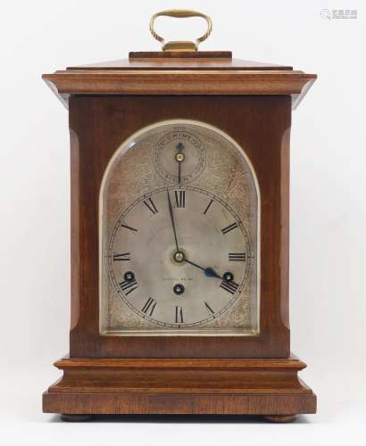 An Edwardian oak bracket clock, the arched silvered dial wit...