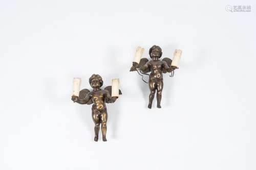 A pair of patinated bronze torch-carrying cherub-shaped two-...