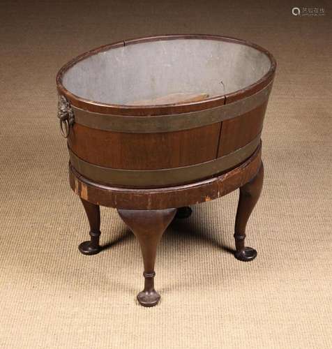 A Mahogany Wine Cooler (A/F). The oval brass bound vessel ha...