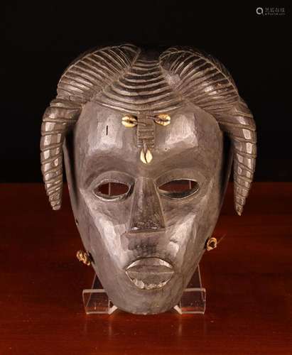 An African Mask decorated with three cowry shells and downsw...