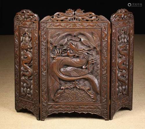 An Oriental Hardwood Triptych Screen boldly carved in relief...