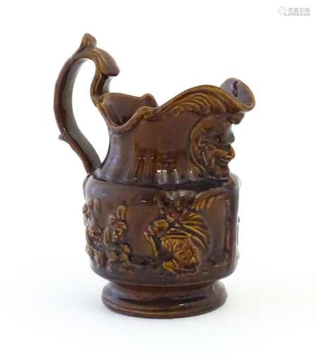 A treacle glazed jug with monkey and mask detail. Approx. 6 ...