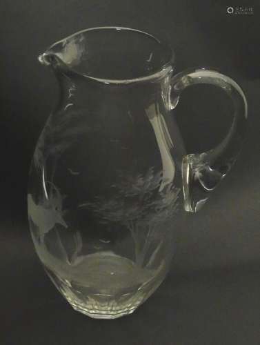 A glass jug with loop handle decorated with etched Alpine Ib...