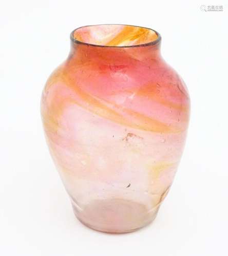 A hand blown art glass vase with peach and pink detail. In t...