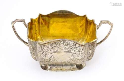 A silver sugar basin with twin handles, engraved foliate det...