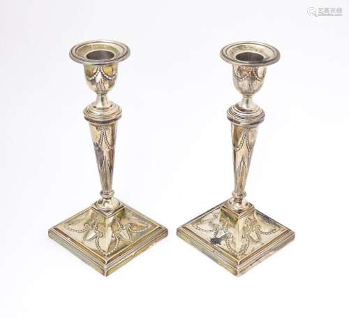 A pair of silver candlesticks with harebell swag and bow dec...