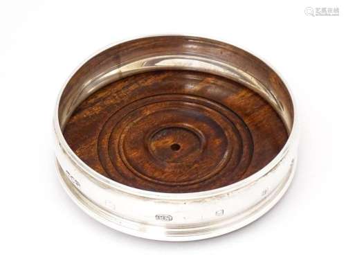 A silver bottle coaster with turned wooden base, hallmarked ...