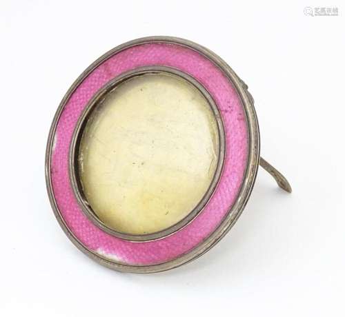 A silver easel back photograph frame of circular form with p...