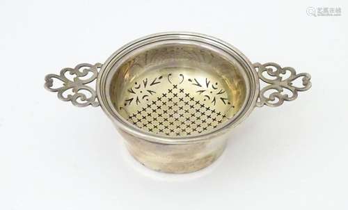 A silver twin handled lemon / tea strainer with pierced deta...