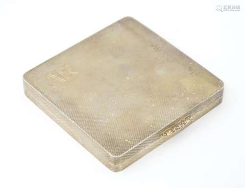 A silver compact of squared form with engine turned decorati...