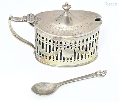 A silver mustard pot with hinged lid, pierced detail and blu...