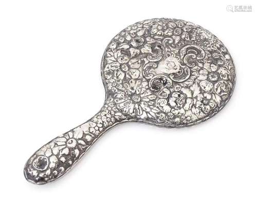 A Victorian silver backed hand mirror with embossed floral a...