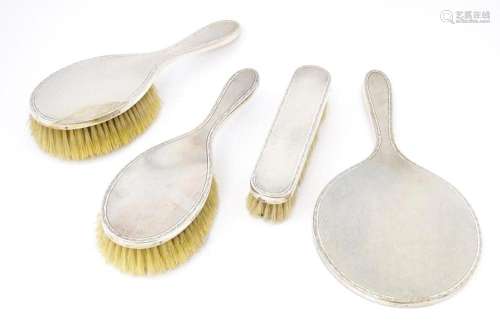 A four piece dressing table set comprising brushes and hand ...