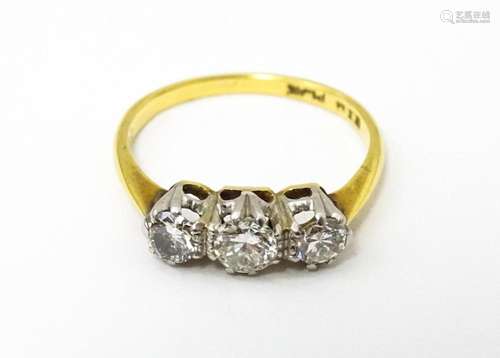 An 18ct gold ring with a platinum set trio of diamonds. Ring...