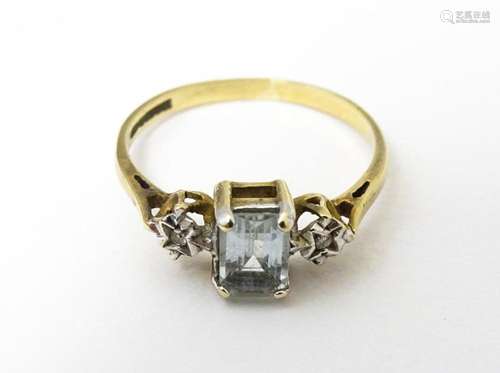 A 9ct gold ring set with central aquamarine flanked by illus...