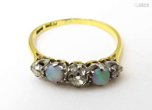 An 18ct ring set with two opals and three diamonds. Ring siz...