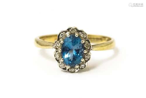 A 9ct ring set with central topaz bordered by diamonds. Ring...