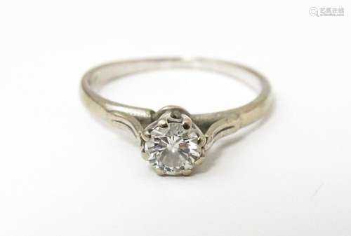 A white metal ring set with central diamond solitaire. Diamo...