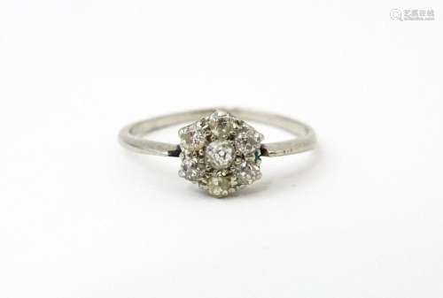 A platinum ring set with six diamonds in a daisy setting. Se...
