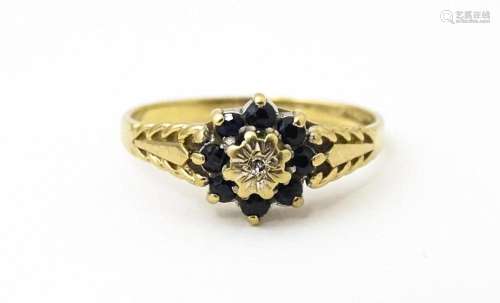 A 9ct gold ring set with central diamond bordered by sapphir...