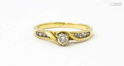 A 9ct gold ring set with central diamond flanked by four fur...