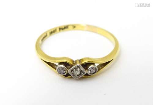 An 18ct gold ring with platinum set central diamond flanked ...