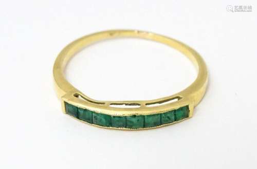 A gold ring set with band of emeralds. Ring size approx. Q