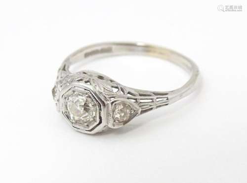 An 18ct white gold ring with central diamond flanked by two ...