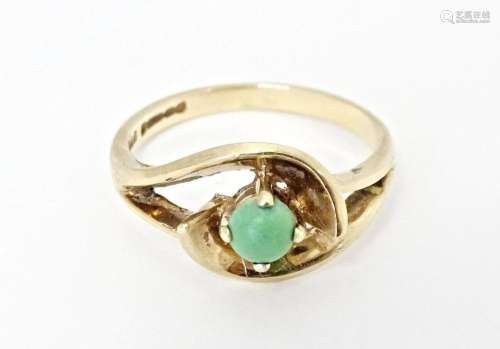 A 9ct gold ring set with central green stone cabochon in an ...