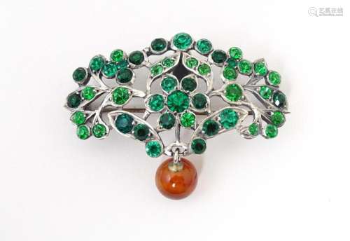 A white metal brooch set with green paste stones and carneli...