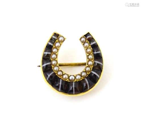 A yellow metal brooch of horseshoe form set with cats eye ca...