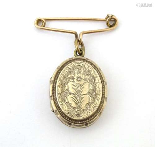 A yellow metal pendant locket with engraved decoration suspe...