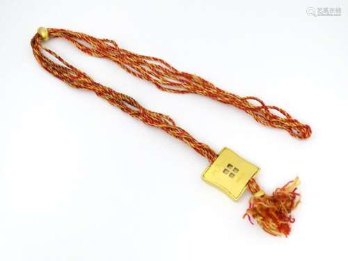 A necklace of twisted orange and golden coloured thread form...