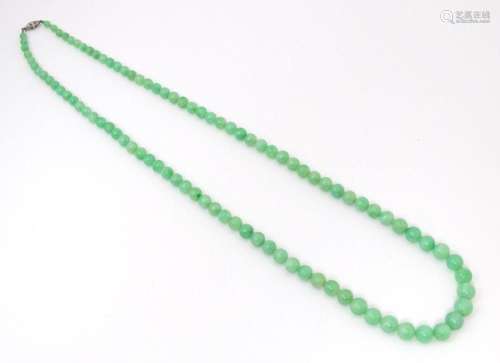 A necklace of graduated green jade beads with white metal cl...