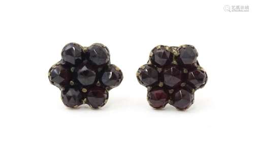 A pair of silver stud earrings decorated with garnets set in...
