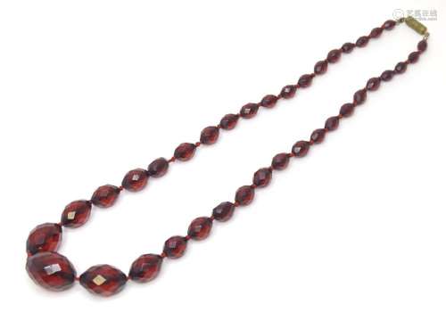 A necklace of facet cut graduated cherry amber coloured bead...