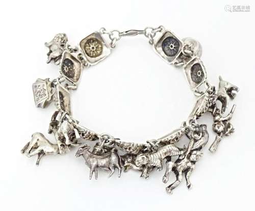 A white metal bracelet set with 13 white metal charms. Appro...